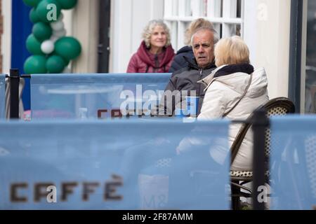 Chichester, Regno Unito. 12 Aprile 2021. I membri del pubblico potranno gustare bevande rinfrescanti al di fuori del caffe Nero, in quanto i negozi non essenziali e altre aziende si riaprono in quanto le restrizioni di blocco dell'Inghilterra sono attenuate. Credit: Paul Terry Photo/Alamy Live News Foto Stock