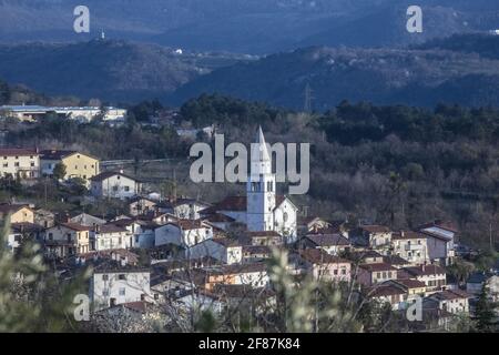 Tardo Afternon Tiro di Villaggio di Osek nella Valle di Vipava Slovenia. Situato nel mezzo della Valle. Surrogato da colline e zona coltivata. Molti Mon sacrale Foto Stock
