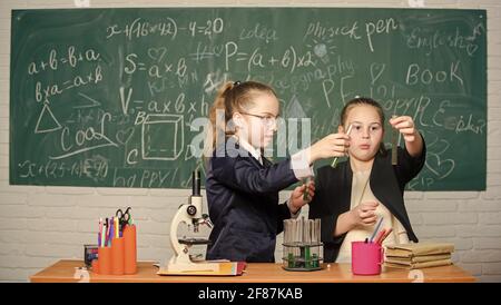 Alla ricerca di una soluzione medica adeguata. Lo scienziato piccolo lavora con il microscopio. Bambine in laboratorio. Educazione chimica. Esperimenti scientifici in chimica Foto Stock