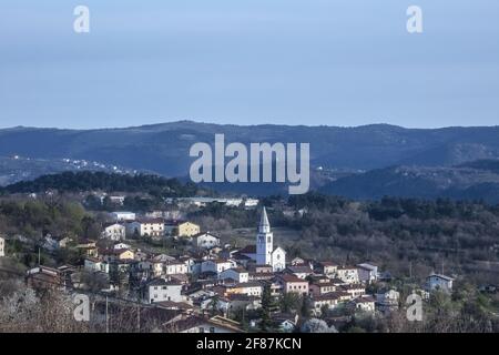 Tardo Afternon Tiro di Villaggio di Osek nella Valle di Vipava Slovenia. Situato nel mezzo della Valle. Surrogato da colline e zona coltivata. Molti Mon sacrale Foto Stock