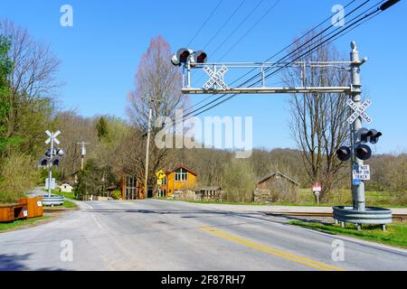 Embreeville, PA, Stati Uniti d'America - 6 aprile 2021: Un attraversamento ferroviario con luci di avvertimento elettriche aeree nella contea rurale di Chester, PA. Foto Stock