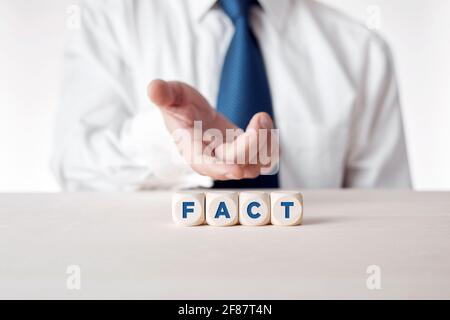 Mano di un uomo d'affari che presenta i cubetti di legno con la parola fatto. Fatti, verità o informazioni accurate in media news o business concept. Foto Stock