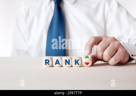 Mano di uomo d'affari sta girando un cubo di legno con le frecce che simboleggiano che il rango sta andando su o giù. Valutazione, classificazione, soddisfazione del cliente o eva Foto Stock