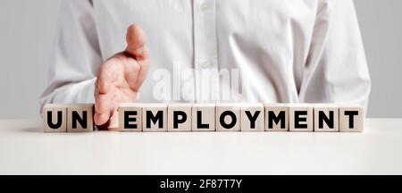 Mano di uomo d'affari mette via le prime due lettere dalla parola disoccupazione e la trasforma in occupazione. Risolvere il problema della disoccupazione. Foto Stock