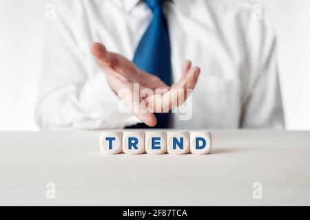 Mano di un uomo d'affari che presenta i cubi di legno con la tendenza parola. Nuovi argomenti, tendenze, temi, stili e nuove tecnologie. Foto Stock