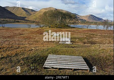 Vista verso Loch awe in Argyll e Bute, Highlands scozzesi con passerelle che formano la linea di guida verso piccoli boschi collinari, lago d'acqua e mountai Foto Stock