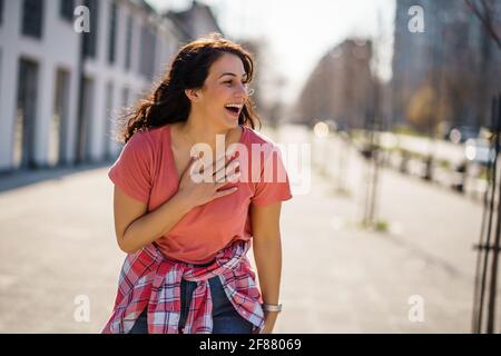 Felice giovane donna sta godendo di una giornata di sole all'aperto in città. Foto Stock