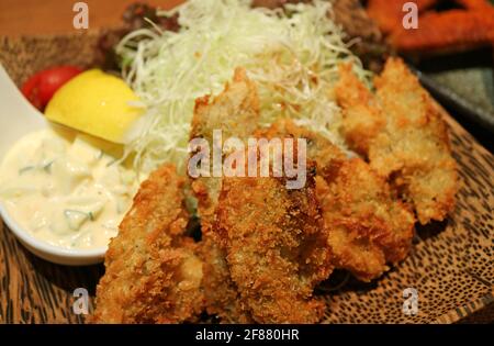 Closeup piatto giapponese di ostriche fritte profonde o Kaki Furai Condito con salsa Tartar e cavolo grattugiato Foto Stock