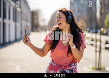 Felice giovane donna sta godendo di una giornata di sole all'aperto in città. Foto Stock