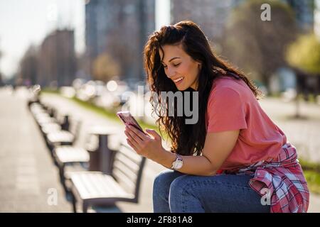 Felice giovane donna sta godendo di una giornata di sole all'aperto in città. Foto Stock