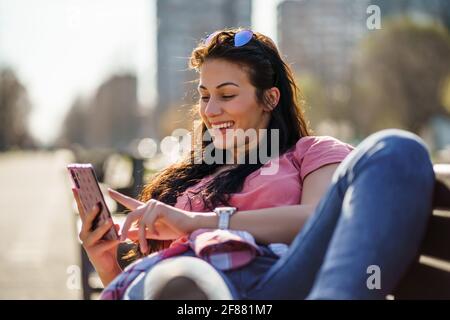 Felice giovane donna sta godendo di una giornata di sole all'aperto in città. Foto Stock