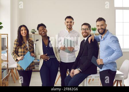 Il team di giovani colleghi molto contenti ha una divertente risata in ufficio verticale Foto Stock