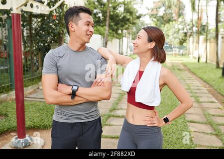 Felice giovane coppia asiatica in piedi in città parco e guardare l'uno all'altro dopo aver finito di lavorare Foto Stock