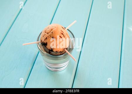 Avocado in un bicchiere d'acqua. Bastoni di legno sono bloccati nell'osso. Germinare semi di avocado. Foto Stock