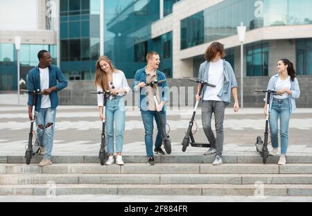 Cinque amici che hanno una piacevole corsa su scooter a calcio motorizzati Foto Stock