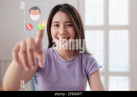 Ritratto di bella donna e sorridente utilizzando la videochiamata su schermo visivo con i suoi genitori. Quarantena e lavoro dal concetto domestico. Foto Stock