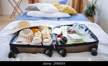 Valigia aperta confezionata per le vacanze a letto a casa, concetto di coronavirus. Foto Stock