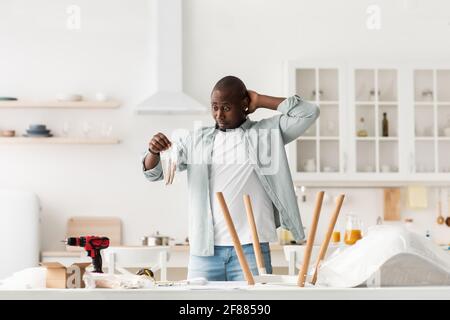 Confezione di tenuta uomo nero confuso con dettagli, tavolo di montaggio con istruzioni, in cucina interna, spazio per la copia. Foto Stock