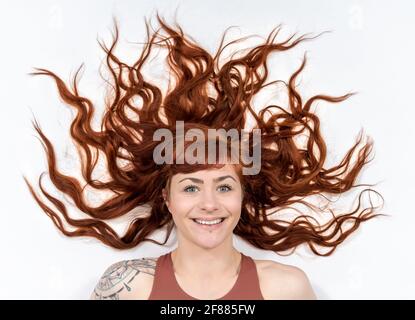 Ritratto di donna con capelli rossi davanti a sfondo bianco con espressione disgustosa del volto e bianco distanziato Foto Stock