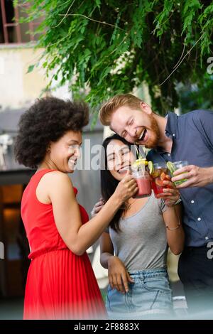 Gruppo di amici diversi che parlano e si divertono al bar all'aperto Foto Stock