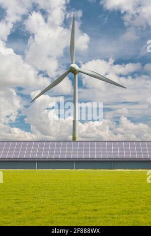 Casa colonica olandese moderna con tetto a pannelli solari di fronte una turbina eolica di grandi dimensioni Foto Stock