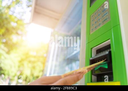 Giovani asiatici che mettono soldi in un distributore automatico per le bevande dal distributore automatico. Messa a fuoco selettiva. Foto Stock