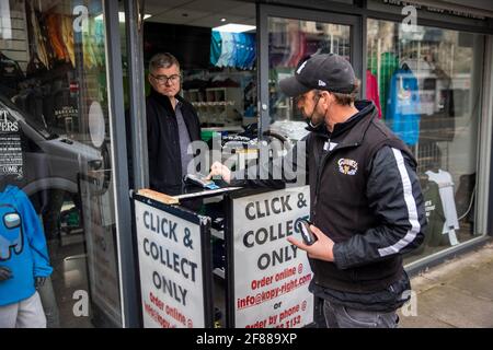 Stephen Seenan, Managing Director di Kopenhaven a Belfast, vende un capo di abbigliamento a un cliente, in quanto le restrizioni di blocco sono attenuate per la prima volta quest'anno in Irlanda del Nord. Data immagine: Lunedì 12 aprile 2021. Foto Stock