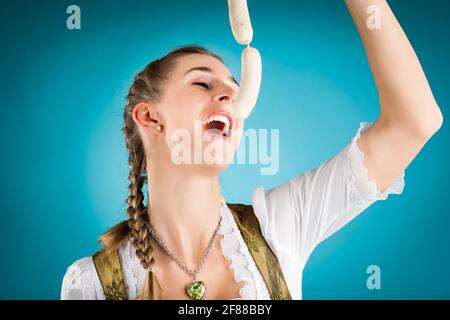 Giovane donna in tradizionali abiti bavarese - dirndl o tracht bianco con salsicce di vitello Foto Stock