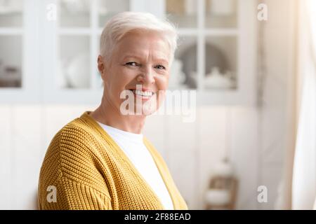 Ritratto di donna anziana felice in posa in cucina Foto Stock