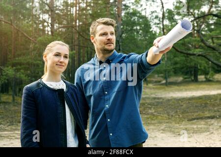 giovane coppia che guarda e sceglie una trama di terra per costruzione di una casa da sogno Foto Stock