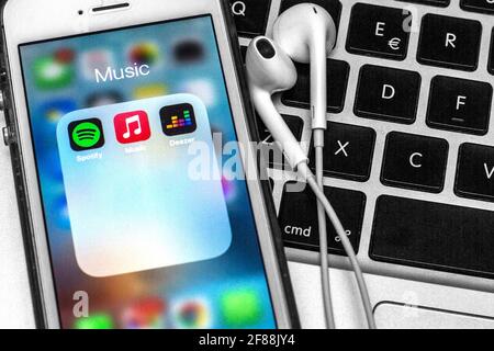 12 aprile 2021, Barcellona, Catalogna, Spagna: In questa illustrazione fotografica, un'app Spotify, Apple Music e Deezer vengono visualizzate su uno smartphone con cuffie su una tastiera per computer portatile. (Immagine di credito: © Thiago Prudencio/DAX via ZUMA Wire) Foto Stock