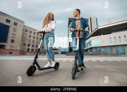 Uomo e donna che cavalcano scooters motorizzati in città Foto Stock