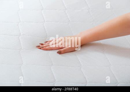 Donna che sceglie il nuovo materasso. Pressione manuale femminile materasso di prova per controllare la morbidezza. Scelta di un comodo materasso per dormire in negozio. Controllo di qualità Foto Stock
