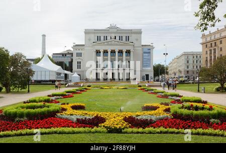 RIGA, Lettonia - 27 luglio 2013: Teatro Nazionale dell'Opera lettone e il bellissimo letto fiorito di fronte Foto Stock