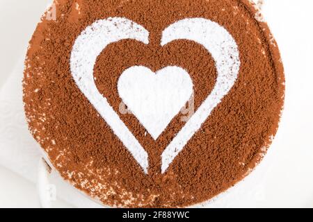 Dessert tiramisù con motivo a forma di cuore da zucchero in polvere e guarnito con cioccolato. Macro. La foto può essere utilizzata come sfondo completo. Foto Stock