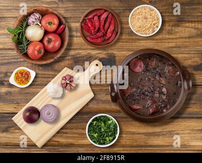 Tradizionale feijoada brasiliana con ingredienti, kale e farina di manioca. Foto Stock