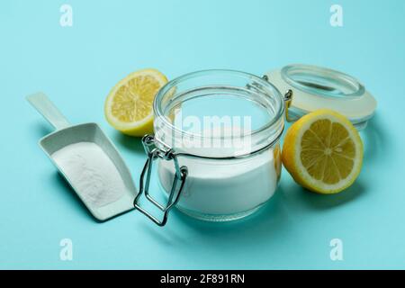 Sessola e vasetto con polvere acida e metà di limone su sfondo blu Foto Stock