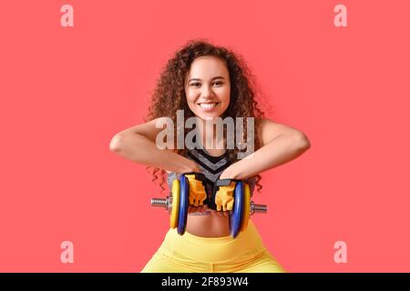 Bella giovane donna allenamento con manubri su sfondo a colori Foto Stock