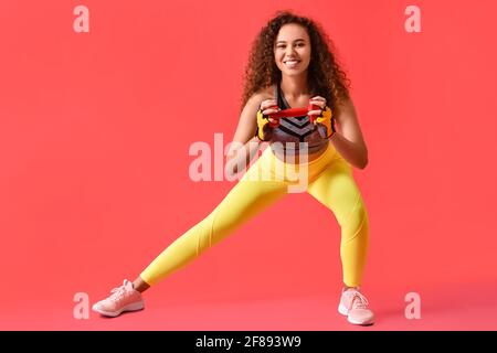 Bella giovane donna allenamento con manubri su sfondo a colori Foto Stock