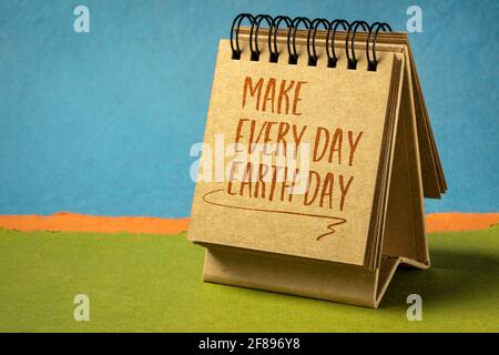 rendi ogni giorno la nota ispiratrice del giorno della terra - la scrittura a mano in un piccolo calendario desktop contro il paesaggio astratto della carta, il concetto ambientale Foto Stock
