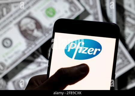 In questa illustrazione della foto, il logo Pfizer della multinazionale farmaceutica americana visualizzato sullo schermo di un dispositivo mobile Android con la valuta dell'icona del dollaro degli Stati Uniti, simbolo dell'icona in dollari sullo sfondo. Foto Stock