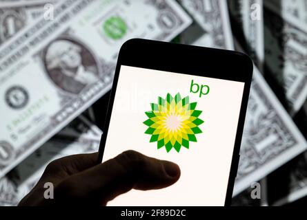 In questa illustrazione fotografica, il plc della British Petroleum Company conosciuto come il logo BP plc è visto sullo schermo di un dispositivo mobile Android con la valuta dell'icona del dollaro degli Stati Uniti, simbolo dell'icona di dollari sullo sfondo. Foto Stock