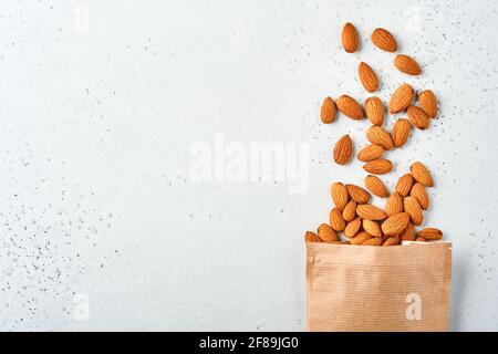 Noce di mandorla in sacchetto di carta su sfondo bianco con spazio per la copia. Snack vegan cibo senza zucchero. Foto Stock