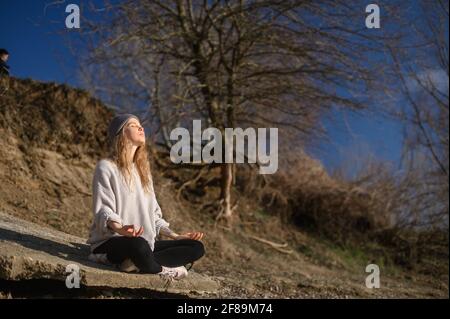 Pratica della meditazione e dell'interazione con la natura. Ragazza vicino al fiume Foto Stock