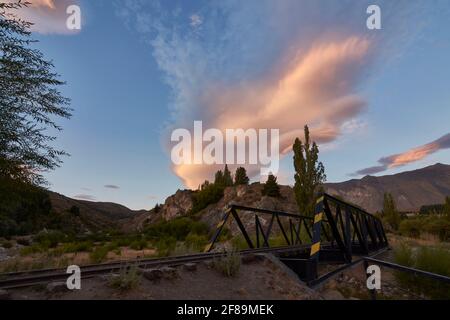 Panorama di un ponte ferroviario di ferro contro le montagne durante il tramonto a Esquel, Patagonia, Argentina Foto Stock