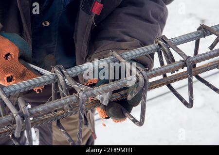 Rinforzo in calcestruzzo. Attrezzo in un cantiere. L'utensile da costruzione per opere monolitiche. I lavoratori devono usare fili di acciaio e pinze per fissare Foto Stock