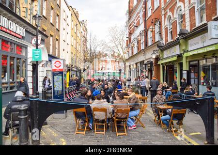 Londra, Regno Unito. 12 aprile 2021. Bar e ristoranti affollati in Old Compton Street, Soho. Negozi, ristoranti, bar e altre aziende hanno riaperto oggi dopo quasi quattro mesi, mentre le ulteriori regole di blocco sono rilassate in Inghilterra. Foto Stock