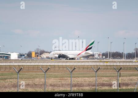 MONACO, GERMANIA - 10 aprile 2021: L'aereo Emirates si trova al terminal dell'aeroporto di Monaco. I viaggiatori partono e salgono a bordo dell'aereo per le loro vacanze Foto Stock