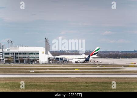 MONACO, GERMANIA - 10 aprile 2021: L'aereo Emirates si trova al terminal dell'aeroporto di Monaco. I viaggiatori partono e salgono a bordo dell'aereo per le loro vacanze Foto Stock