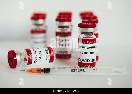 Vaccino Covid-19 - flaconi di vaccinazione con coronavirus. Flaconcini di iniezione e siringa su fondo bianco. La siringa è vuota accanto al flaconcino che si trova in basso. Foto Stock